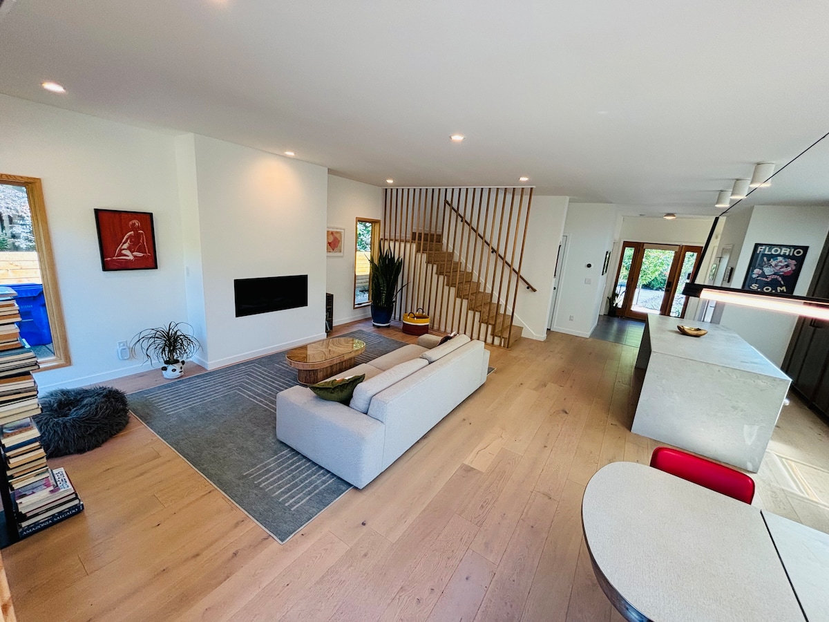 Open-concept living room with modern sectional sofa and wood slatted staircase