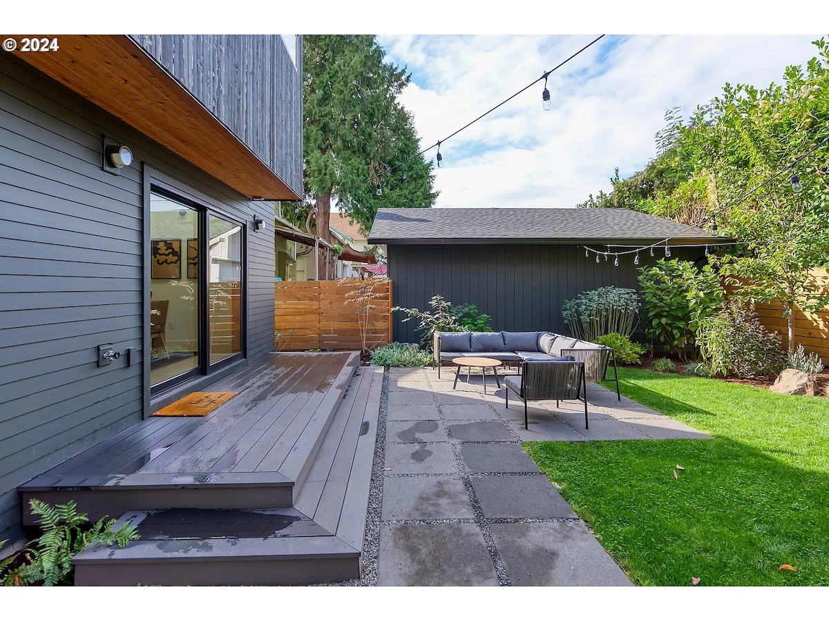 Private backyard patio with deck, lounge seating, and string lights