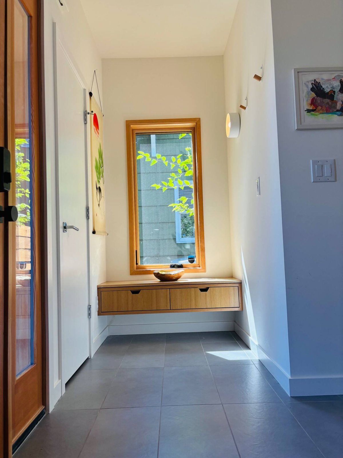 Entry with floating bench, built-in drawers, Calder mobile, and wall sconce