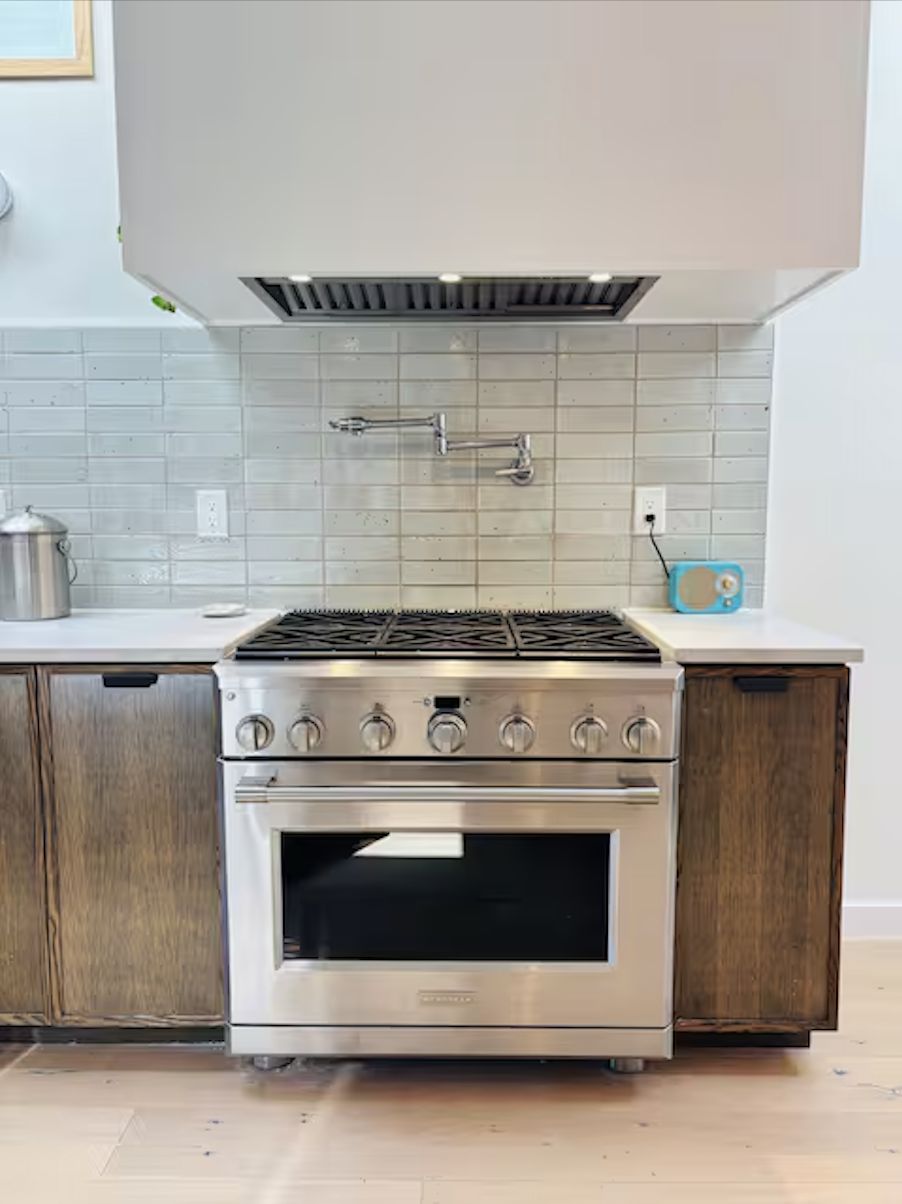 Professional stainless steel gas range with pot filler faucet and custom range hood