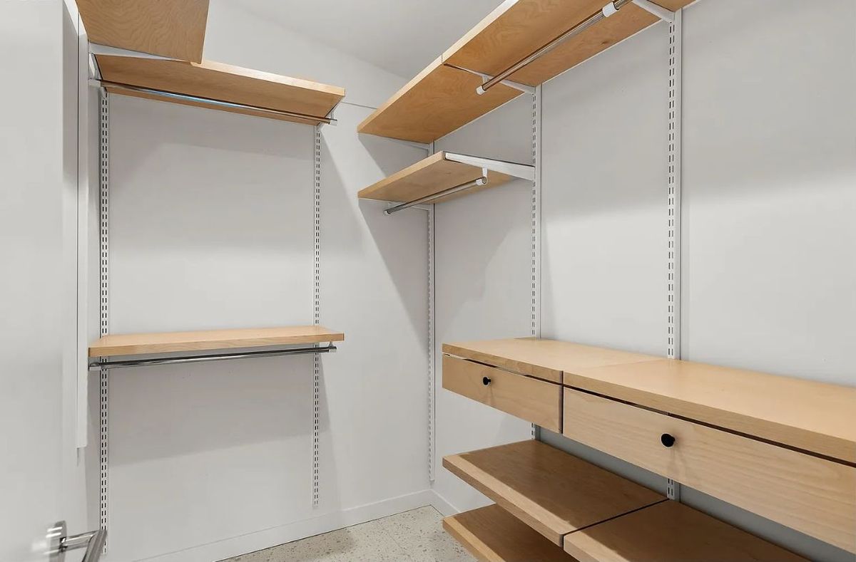 Walk-in closet with adjustable wood shelving, hanging rods, and built-in drawers