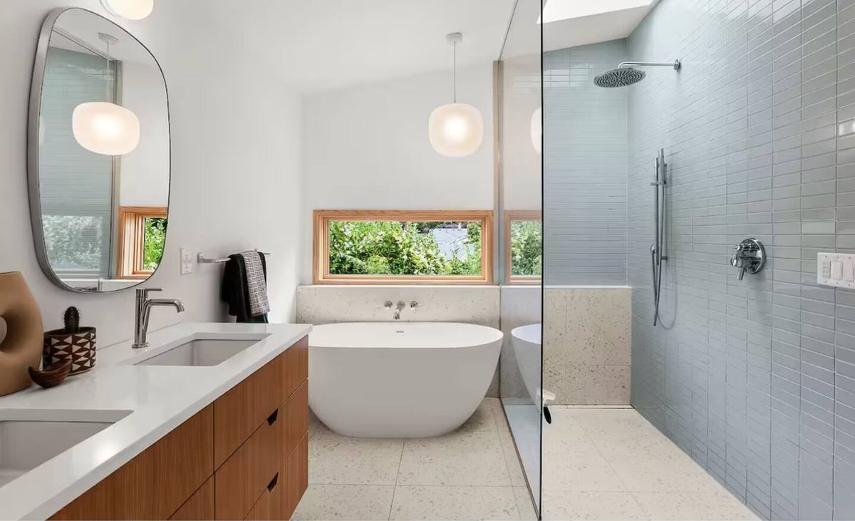 Primary bathroom with freestanding soaking tub, glass rain shower, and skylight